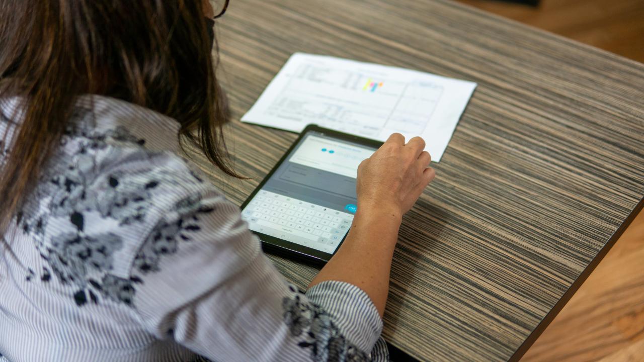 seorang wanita duduk di meja menggunakan tablet