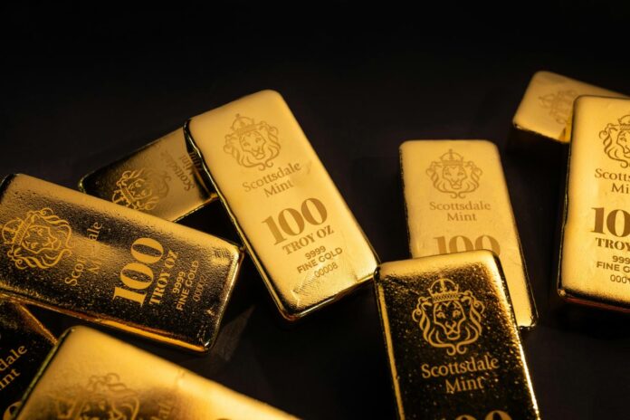 Beberapa emas batangan berserakan di permukaan gelap.